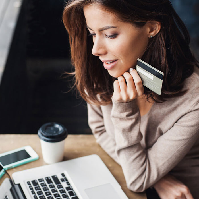 a woman shopping online on her laptop with her debit card